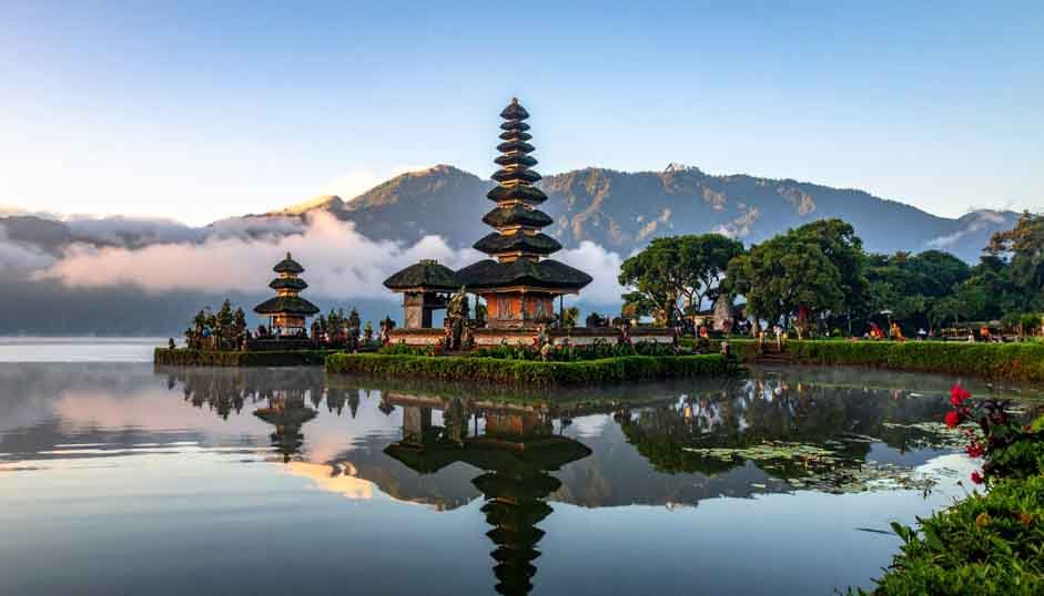 The multi-tiered Meru towers of Ulun Danu Bratan temple reflected in the lake at dawn.